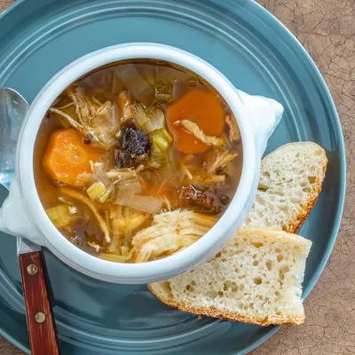 Warm vegetable soup with carrots and celery, served with slices of crusty bread.