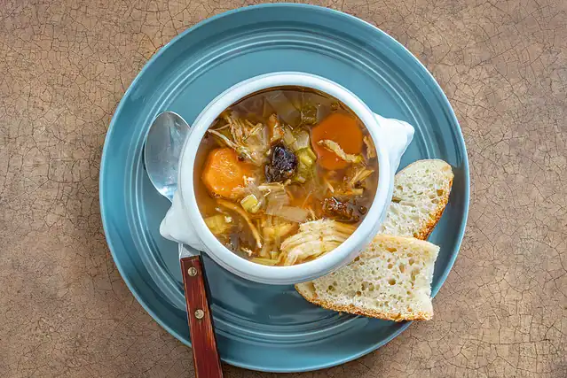 A serving of Instant Pot cock-a-leekie soup (chicken soup with leeks) with crusty bread on the side.