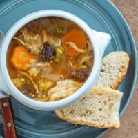 A serving of Instant Pot cock-a-leekie soup (chicken soup with leeks) with crusty bread on the side.