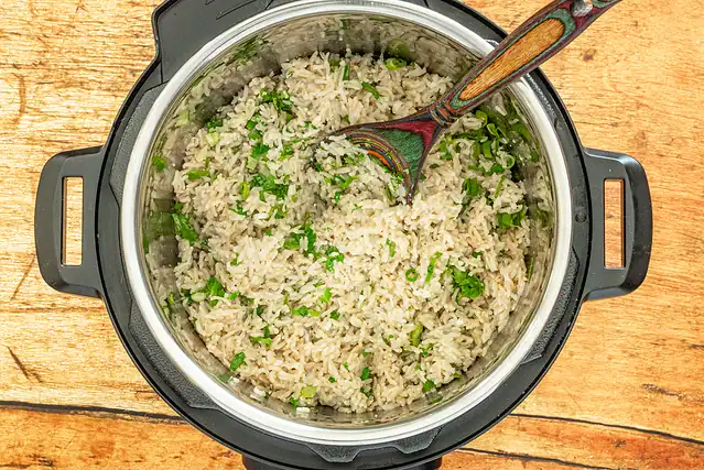 Instant Pot coconut rice prep: fluff the rice and add the green onions and cilantro.
