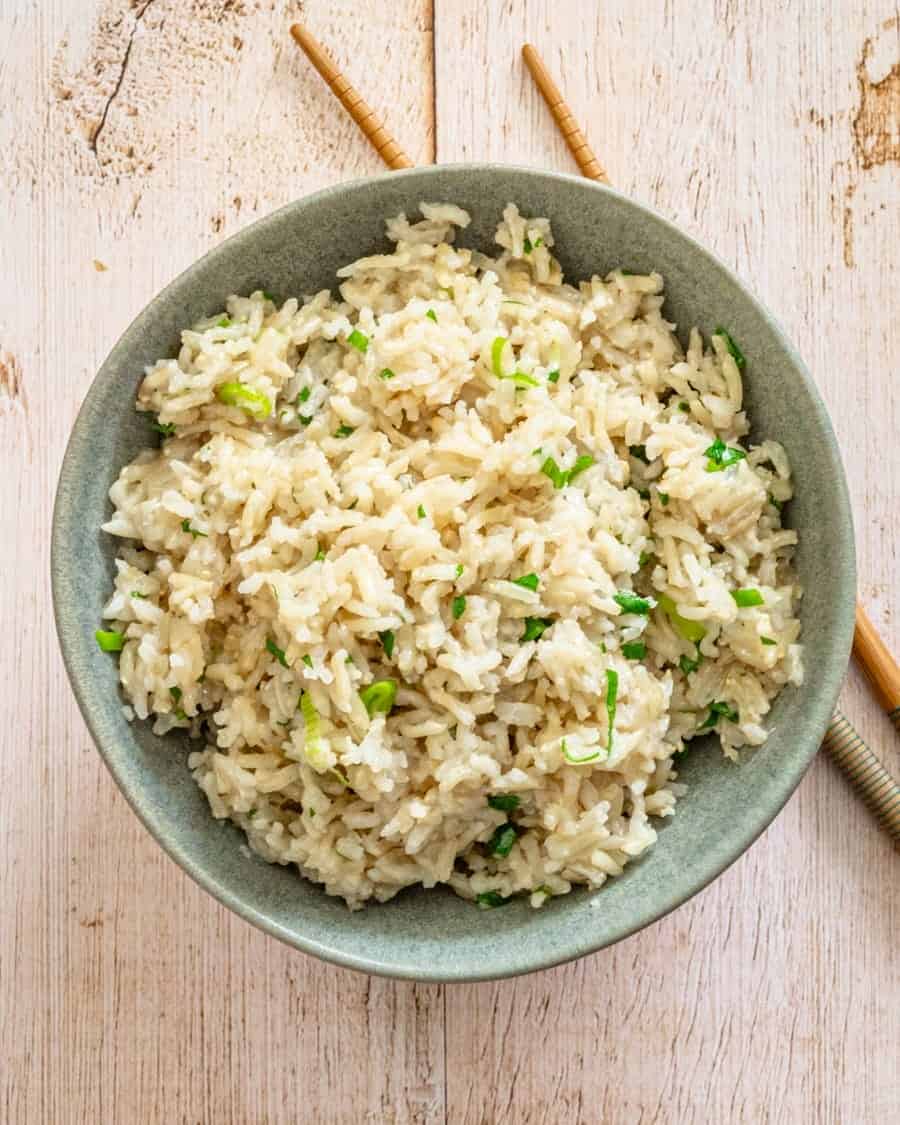 Steamed cauliflower rice with chopped green onions in a gray bowl.