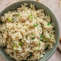 A bowl of coconut brown rice garnished with green onions and cilantro.