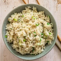Cooked rice with chopped green onions in a bowl.