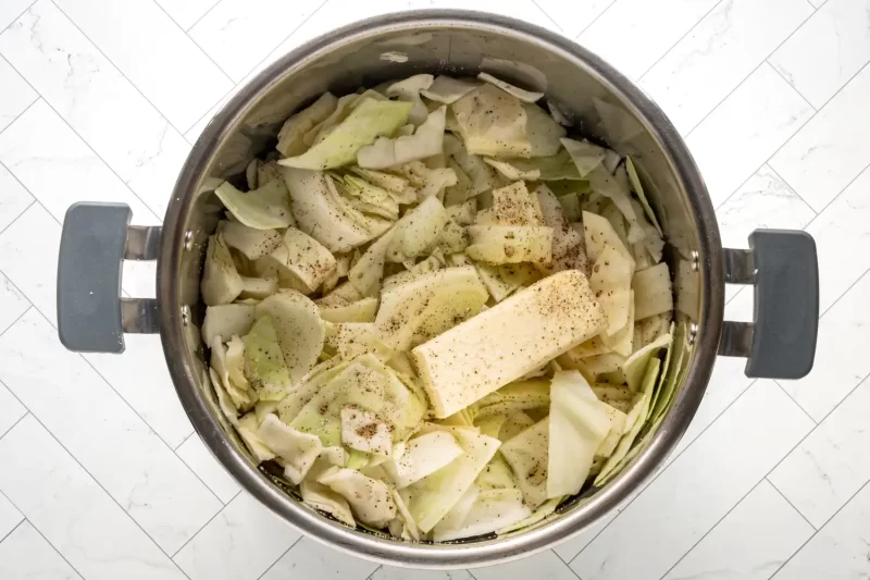 Celery and cabbage chopped in a stainless steel pot with seasoning.