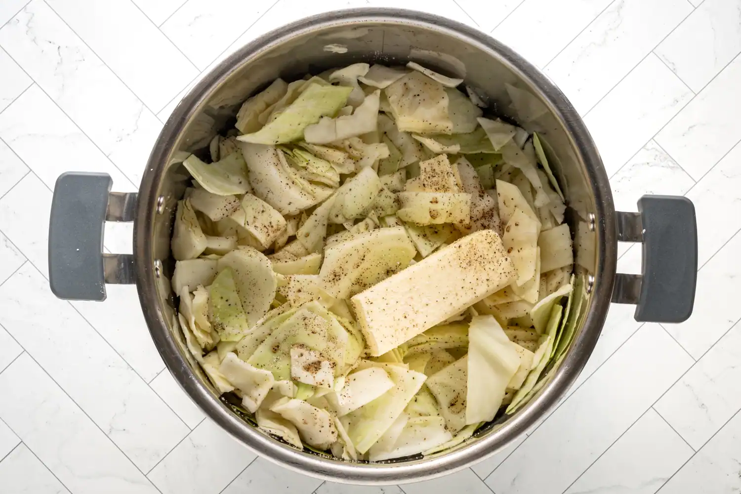 Chopped cabbage in the Instant Pot topped with butter, salt, and pepper.