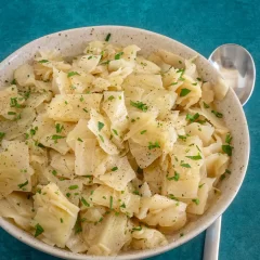 Creamy mashed potatoes garnished with chopped parsley and black pepper.