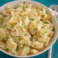 A serving bowl with Instant Pot cooked cabbage, garnished with parsley.