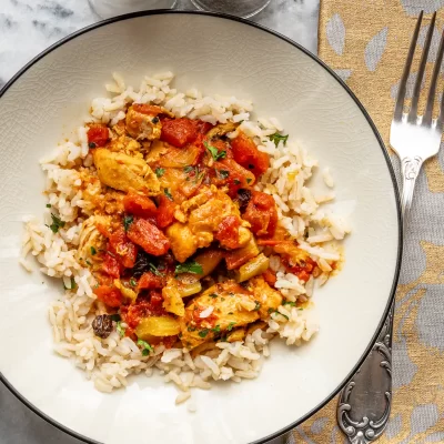 Savory chicken and vegetable stew served over white rice on a decorative plate.