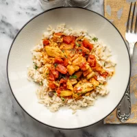 Steamed rice topped with hearty vegetable curry and tender chicken pieces.