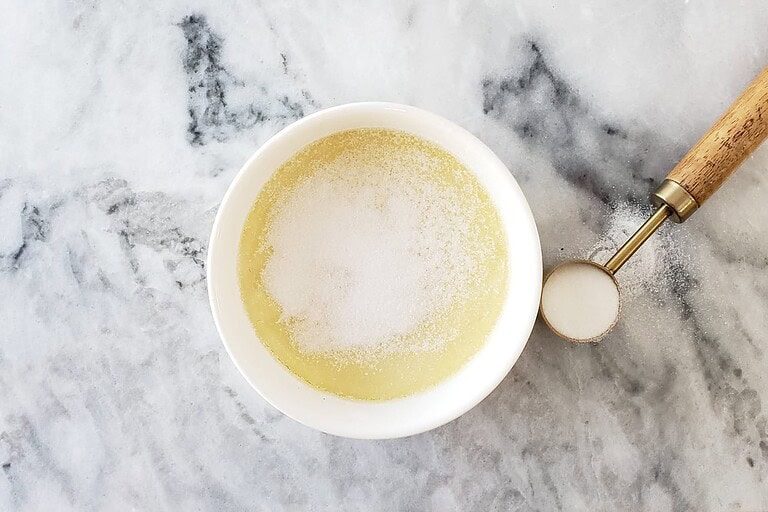 Creamy melted butter in a white bowl on marble surface.