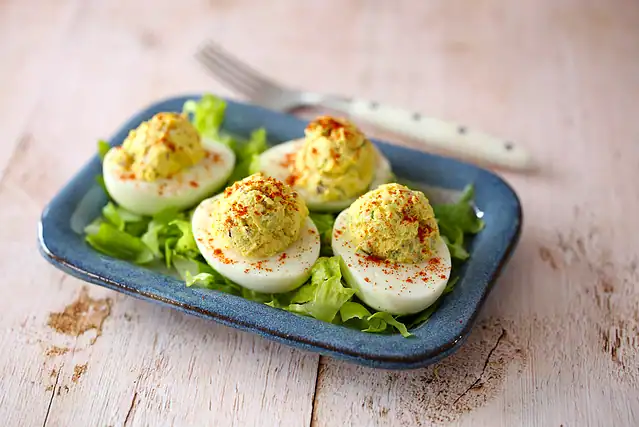 Instant Pot deviled eggs on a bed of lettuce and a sprinkle of paprika.