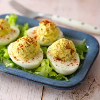 Boiled eggs stuffed with egg salad on a blue plate.