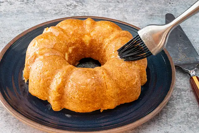 Brushing glaze on the Instant Pot donut cake.