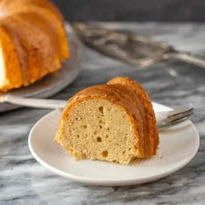 Fluffy vanilla cake slice with caramel glaze on white plate.