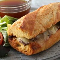 An Instant Pot French dip sandwich with cheese in a toasted crusty roll.