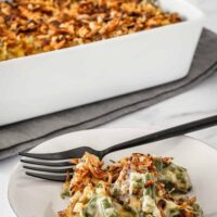 Instant Pot green bean casserole in a baking dish with crispy onion topping and some on a small plate.
