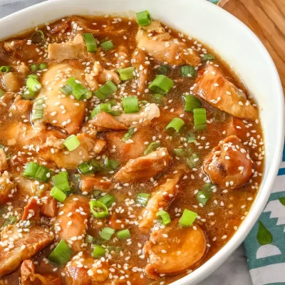 Creamy chicken and vegetable stir-fry with sesame seeds and chopped green onions.