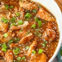 Honey sesame chicken in a serving dish with green onion garnish.