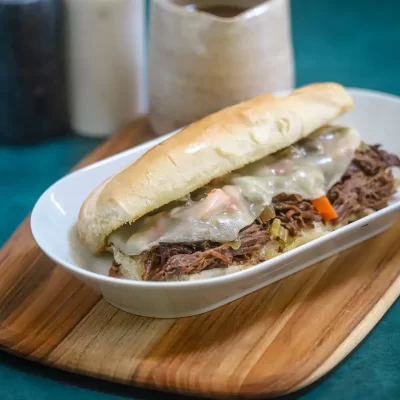 Slow-cooked shredded beef sandwich with melted cheese on a hoagie bun.