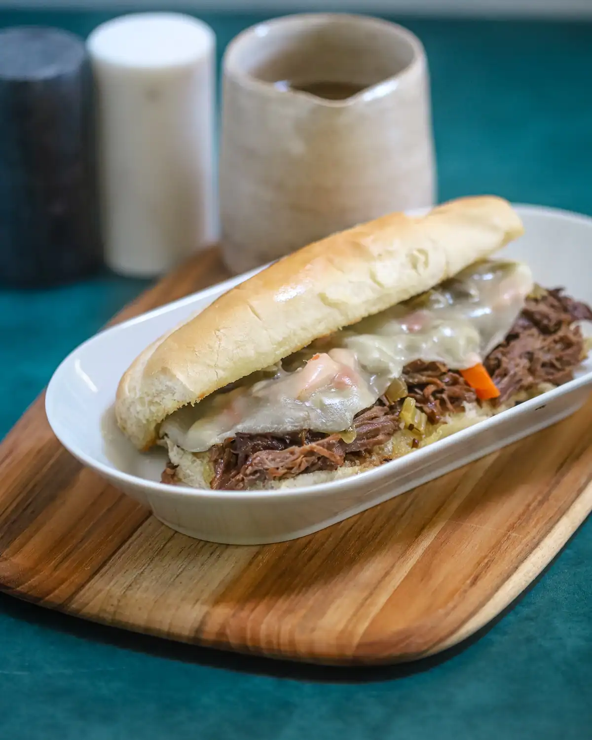 Slow-cooked shredded beef sandwich with melted cheese on a hoagie bun.