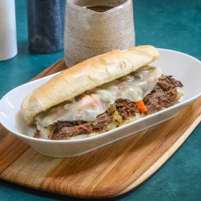 Slow-cooked shredded beef sandwich with melted cheese on a soft bun.