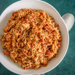 Steamed rice mixed with vegetables and sliced sausage, served in a white bowl.