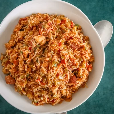 Steamed rice mixed with vegetables and sliced sausage, served in a white bowl.