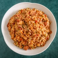 Savory rice dish with vegetables and meat in a white bowl.