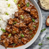 A plate of Instant Pot Korean beef with rice and green onions for garnish.