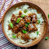 Steamed white rice topped with saucy beef chunks and green onions.