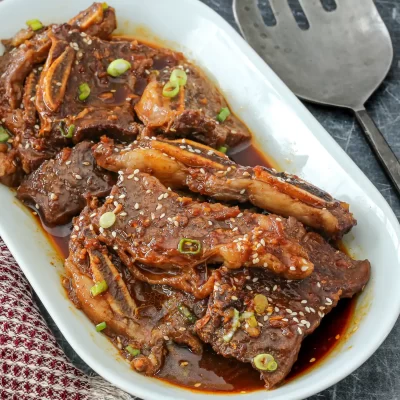 Succulent braised short ribs in rich sauce garnished with sesame seeds and green onions.