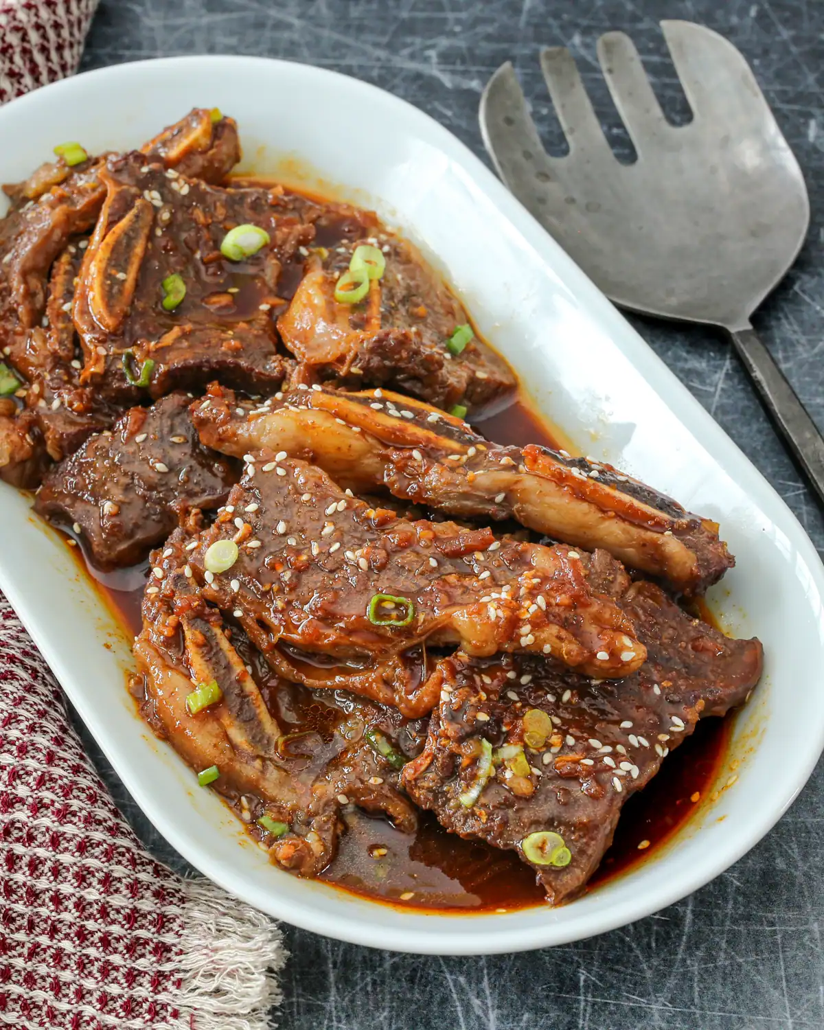 Succulent braised short ribs in rich sauce garnished with sesame seeds and green onions.