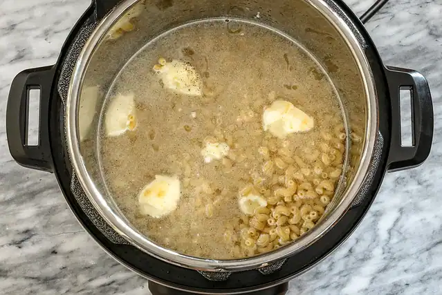Instant Pot mac and cheese preparation with butter and water.
