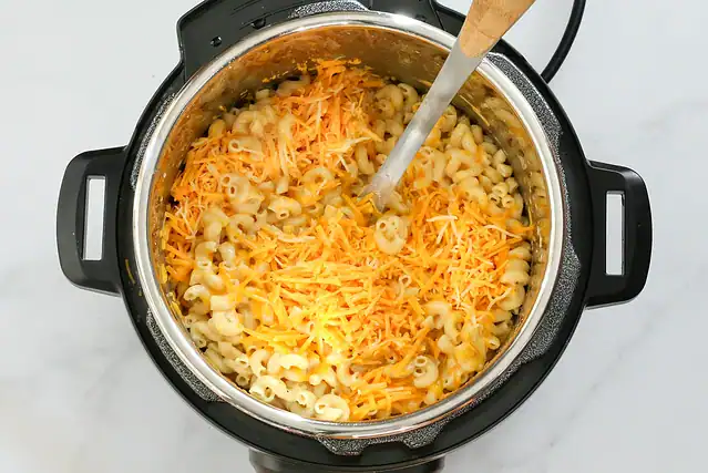 Adding the cheese to the cooked Instant Pot mac and cheese.