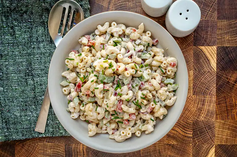 Creamy macaroni salad with chopped vegetables and fresh herbs.