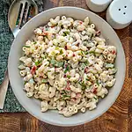 Creamy macaroni pasta salad with vegetables and herbs.