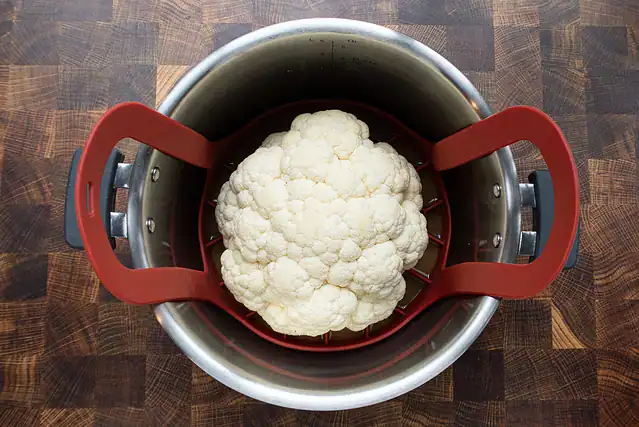 A head of cauliflower in the Instant Pot, ready to pressure cook.