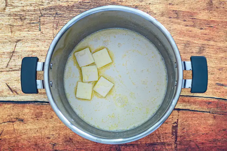 Cream and butter melting in a stainless steel saucepan.