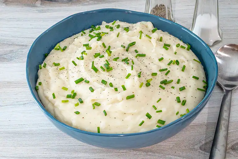 Creamy mashed potatoes topped with chopped green onions and black pepper.