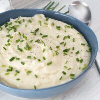 A bowl of Instant Pot pressure cooker mashed potatoes with garnish of herbs.