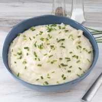 Creamy mashed potatoes topped with chopped chives and black pepper.
