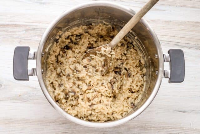 Creamy mushroom risotto cooking in a stainless steel pot.