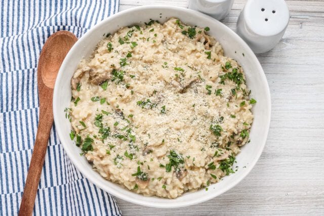 A bowl of Instant Pot mushroom risotto with a garnish of parsley and Parmesan cheese.