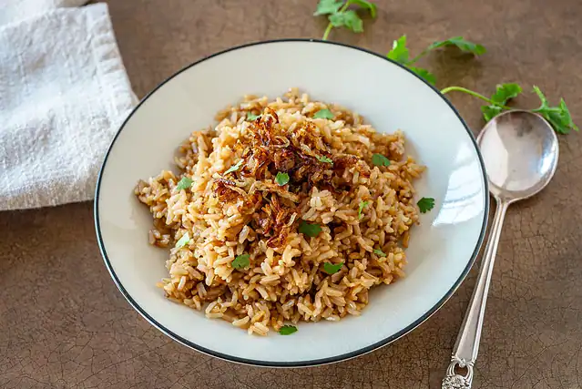 Fluffed Instant Pot Parsi rice is garnished with fried onions and cilantro and ready to eat.