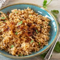 Fluffed Instant Pot Parsi rice is garnished with fried onions and cilantro and ready to eat.