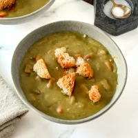 Creamy vegetable soup with croutons and salt in the background.