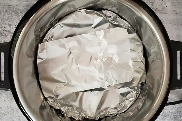 The pear cake is in the Instant pot with a foil cover and sling.