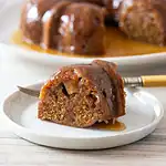 Fried apple dumpling with caramel sauce on a white dish.