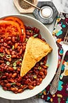 Baked fish fillet with side of beans and sliced tomatoes on a white oval plate.