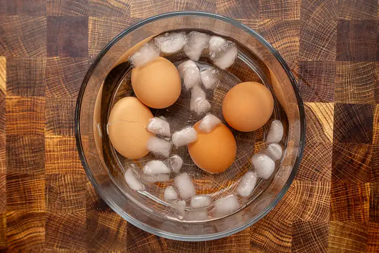 Fresh eggs submerged in water with ice cubes.